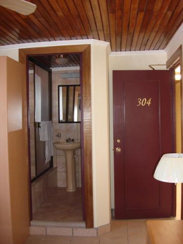 a bathroom with a toilet and a sink and a door at Hotel La Guaria Inn & Suites in Alajuela City