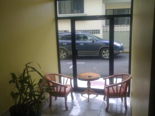 a table and chairs in a room with a window at Hotel La Guaria Inn & Suites in Alajuela City