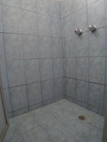 a shower with a tile floor and a drain at Hotel La Guaria Inn & Suites in Alajuela City