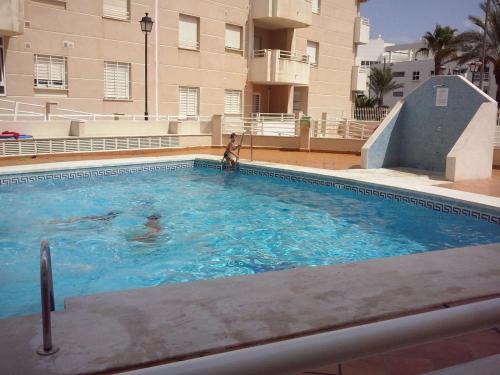 una chica en una piscina en un edificio en Apartamento con piscina y terraza a 50 metros de la playa, en Roquetas de Mar