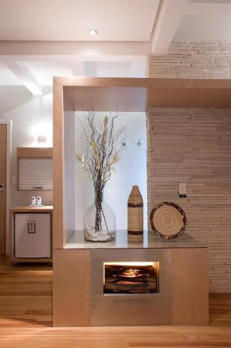 a fireplace in a living room with a vase of flowers at Motel Acaso (Adults Only) in São Paulo