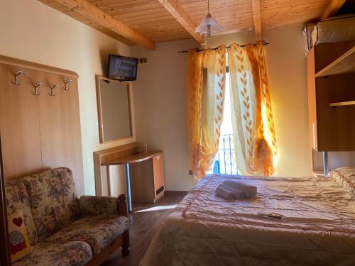 a bedroom with a bed and a couch and a window at La casetta della nonna in Caramanico Terme
