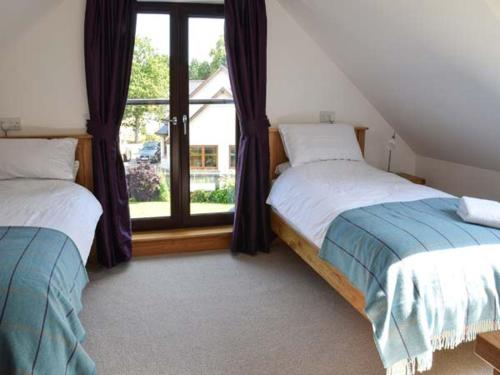 a bedroom with two beds and a large window at Little Chestnut in Muir of Ord
