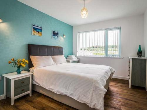 1 dormitorio con 1 cama grande y pared azul en Tigh Na Sith, en Aultbea