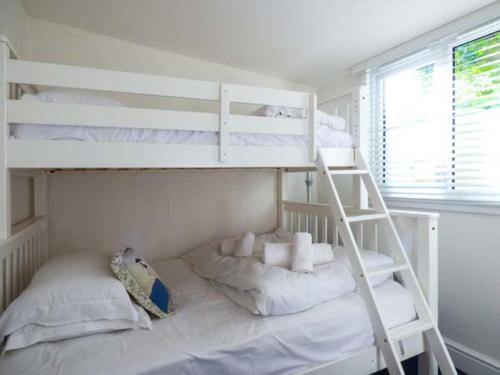 a bedroom with two bunk beds and a ladder at Tidewood in Polzeath