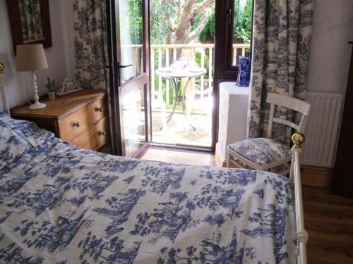 a bedroom with a bed with a blue and white blanket at Groom Cottage in Bude