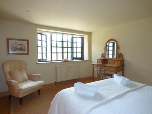 a bedroom with a bed and a chair and a desk at Meadow Cottage in Fowey