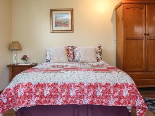 a bedroom with a bed with a red and white bedspread at Sunny Cabin in Tintagel