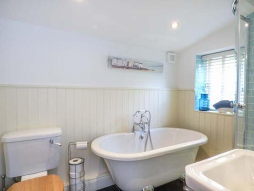 a bathroom with a tub and a toilet and a sink at Bee Hive Cottage in Morwenstow