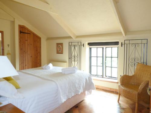 a bedroom with a white bed and a window at Old Winery Cottage in Golant