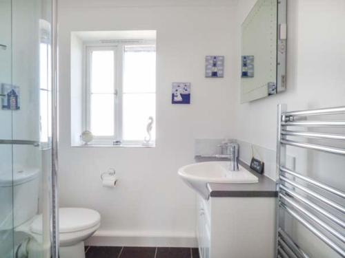 a white bathroom with a toilet and a sink at 7 Harlyn Cottages in St Merryn