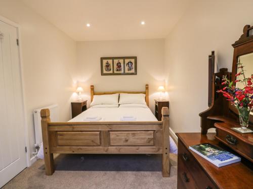 Un dormitorio con una cama y una cómoda de madera. en The Coach House, en Bodmin