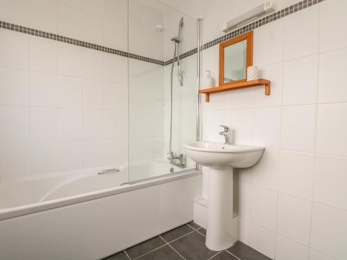 a white bathroom with a sink and a bath tub at Shoreline in Marazion