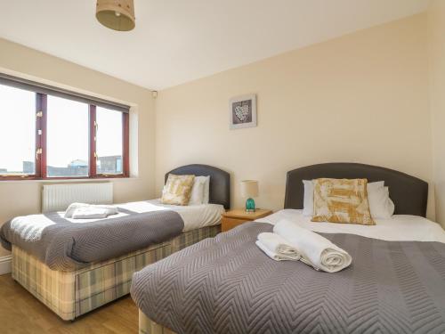 two beds in a room with two windows at Surfside in Marazion
