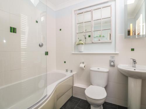 a white bathroom with a toilet and a sink at Tides in Padstow