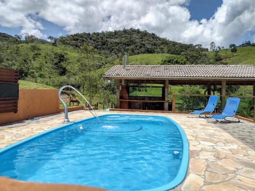uma piscina com duas cadeiras e um gazebo em Rancho Zé Valentim em São José dos Campos