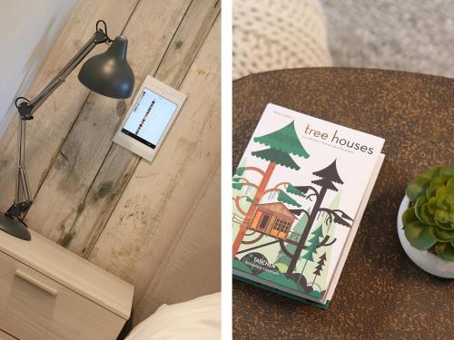 a table with a book and a lamp and a tree house at Pig House, Boskensoe Barns in Helford Passage
