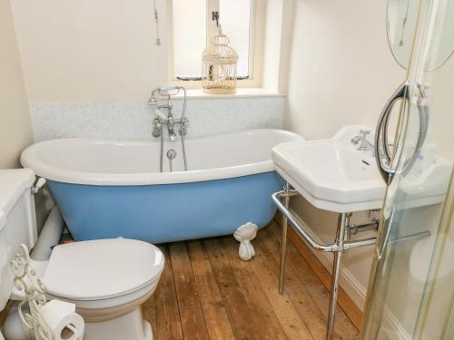 a bathroom with a tub and a toilet and a sink at Sandy Cottage in Linton