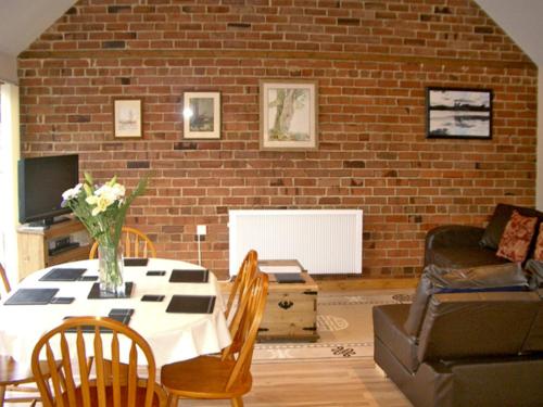 a living room with a table and a brick wall at Happy Union Stables in Abbey-Cwmhir
