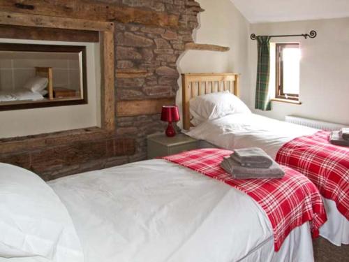 a bedroom with two beds and a stone wall at Bushmills in Bacton