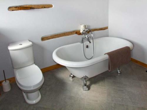 a bathroom with a white tub and a toilet at Bushmills in Bacton