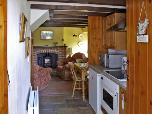 a kitchen with a living room with a fireplace at Church Barn in Tissington