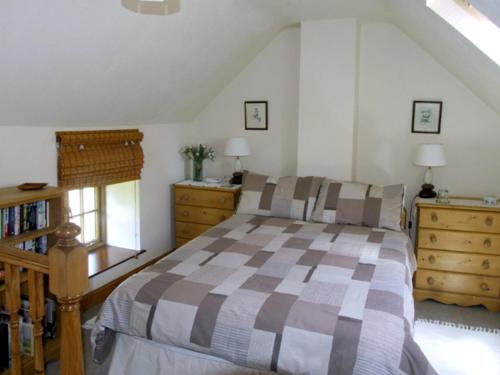 a bedroom with a bed and two dressers and a window at Church Barn in Tissington