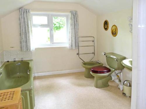 a bathroom with two toilets and a green tub and sink at High Sprintgill Cottage in Ravenstonedale