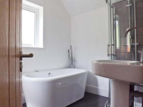 a white bathroom with a tub and a sink at Llechwedd in Dolgellau