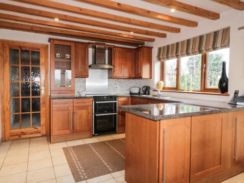 a kitchen with wooden cabinets and a stove top oven at Lynton House in Drybrook