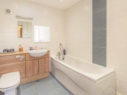 uma casa de banho com uma banheira, um lavatório e um WC. em Ridge Cottage em Longwitton