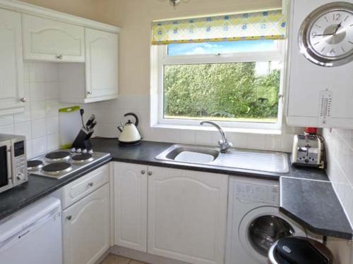 a white kitchen with a sink and a window at Seascope in Kessingland