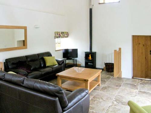 a living room with a black leather couch and a table at Nant yr Hendre in Llanfair-Dyffryn-Clwyd