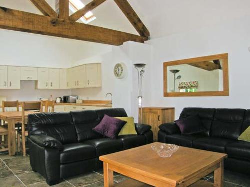 a living room with two black couches and a table at Nant yr Hendre in Llanfair-Dyffryn-Clwyd