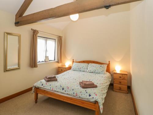 a bedroom with a bed and two lamps and a window at Corner Barn in Winterborne Stickland