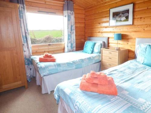 sypialnia z 2 łóżkami w drewnianym domku w obiekcie Ty Pren w mieście Porthgain