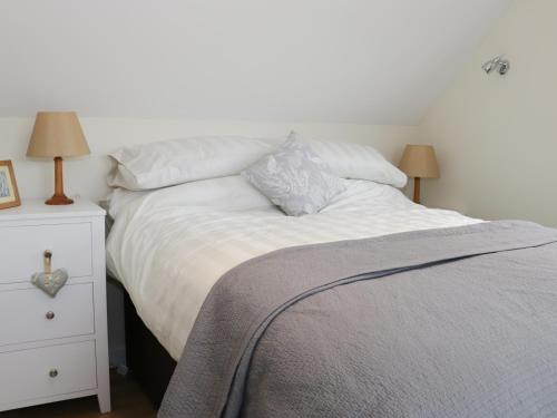 a bed with white sheets and pillows next to a night stand at Bicton Lodge in Clun