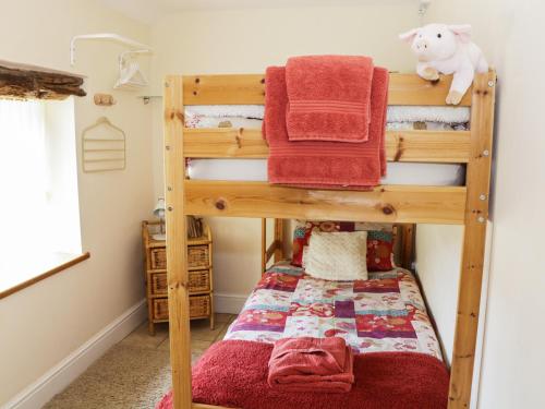a bunk bed with red towels on top of it at Piggery Cottage in Wigton