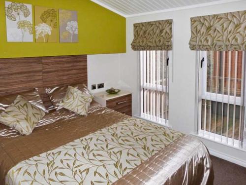 a bedroom with a large bed and two windows at High View Lodge in Windermere