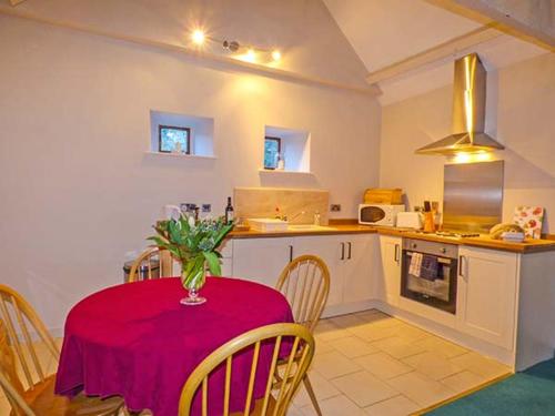 a kitchen with a table with a red table cloth on it at The Aylesbury Cottage in Dyrham