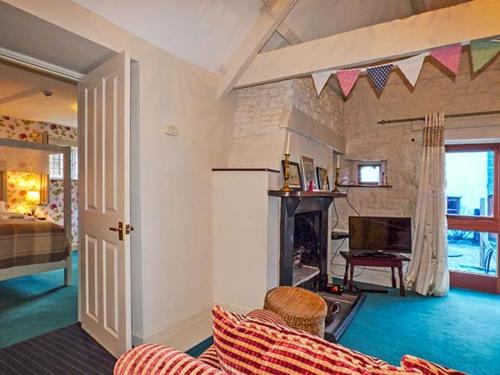 een woonkamer met een bank en een open haard bij The Aylesbury Cottage in Dyrham