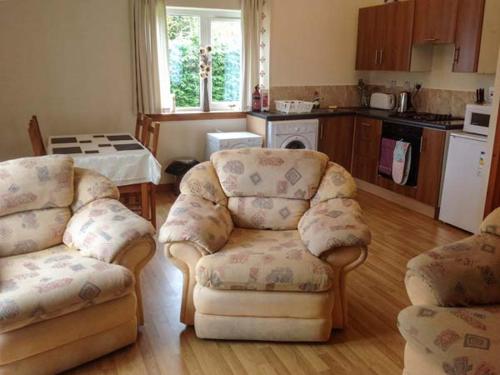 a living room with two chairs and a kitchen at Cooinda Cottage in Morar