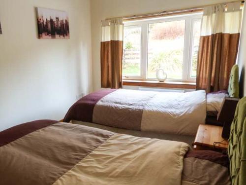 a bedroom with two beds and a window at Cooinda Cottage in Morar