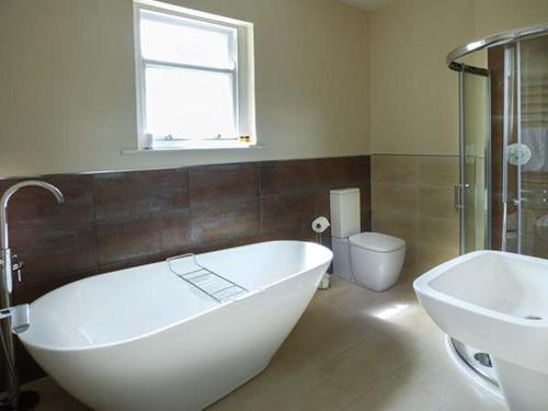 a bathroom with a tub and a sink and a toilet at Cringles House in Silsden