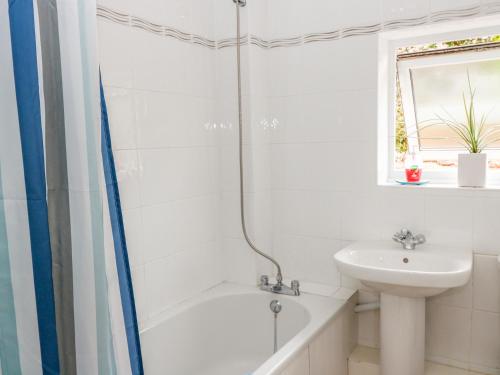 a white bathroom with a sink and a tub and a toilet at Fowey Cottage in Coffinswell