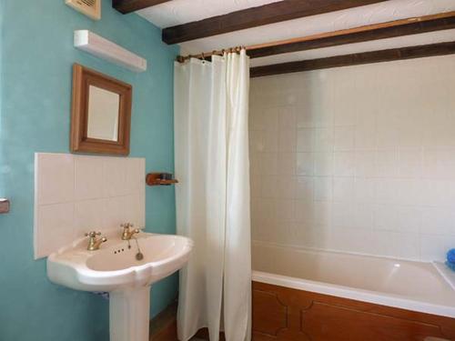 a bathroom with a sink and a white shower curtain at Chevinside Cottage in Hazelwood