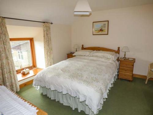 a bedroom with a large bed and a window at Harvest Cottage in Levisham