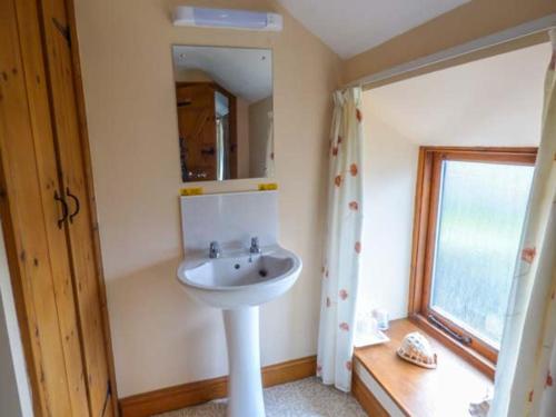 a bathroom with a sink and a mirror and a window at Harvest Cottage in Levisham
