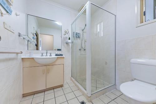 a bathroom with a shower and a sink and a toilet at Airlie Sunset Waterview Apartment in Airlie Beach