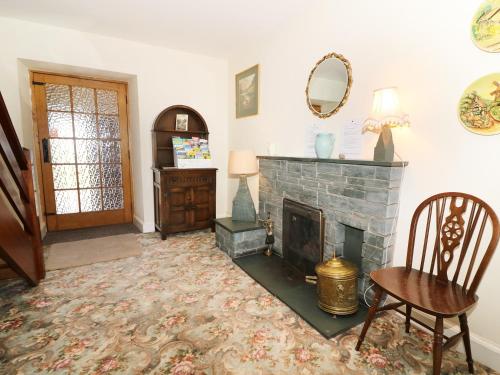 ein Wohnzimmer mit einem Kamin, einem Tisch und einem Stuhl in der Unterkunft Ghyll Bank House in Staveley